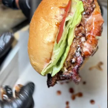 A Fri Kitchn burger held up in a gloved hand.