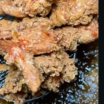 Battered chicken frying in hot oil at Fri Kitchn.